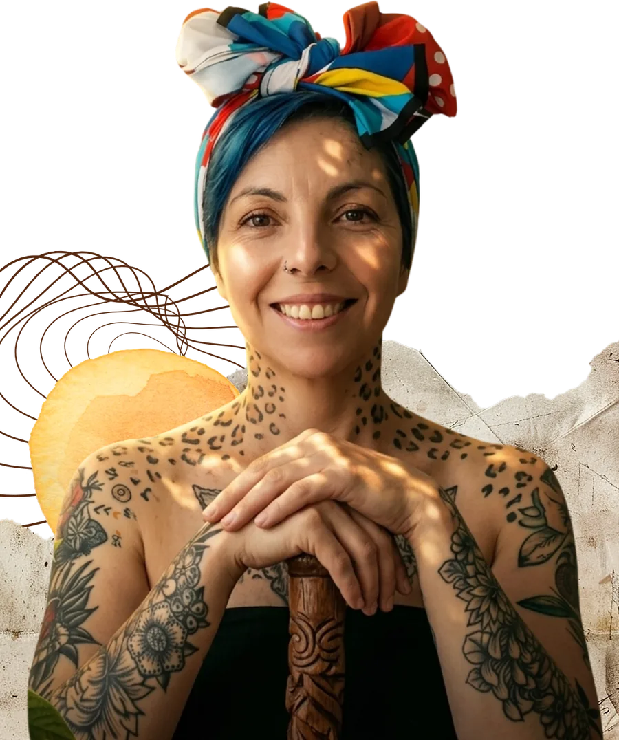 Nathalia Andrea Velasco sonriendo, con turbante de colores y los brazos tatuados apoyados sobre un bastón de madera