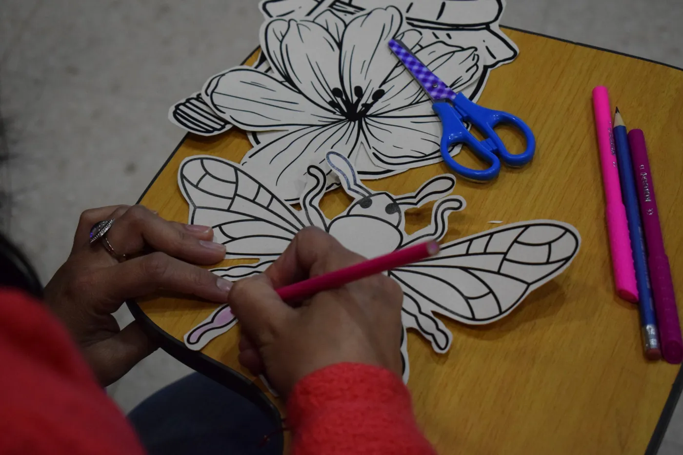 Manos que colorean con calma una abeja dibujada sobre papel