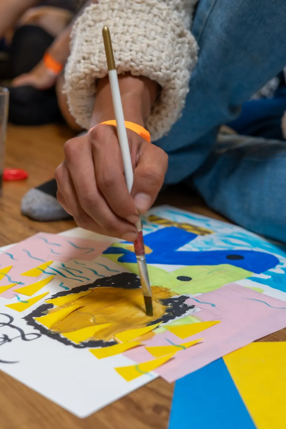 Mano que pinta con pincel sobre un papel lleno de color